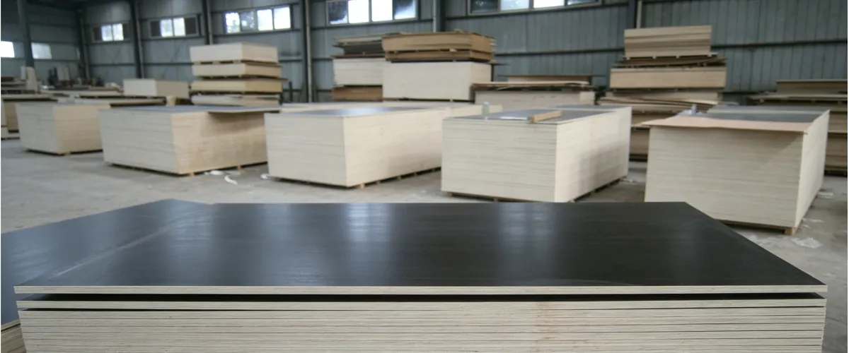Wholesale film faced plywood sheets stacked in a warehouse for bulk construction and concrete formwork projects.